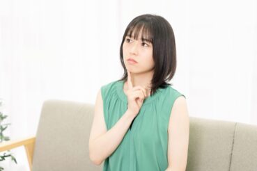 顎に人差し指を置いて考えている女性