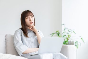 ソファーの上で悩む女性
